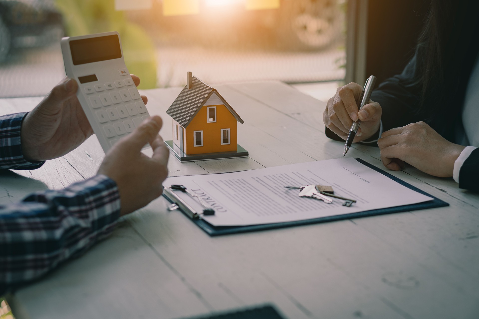 Immobilienfachleute bieten ihren Kunden Verträge an, um Hauskäufe, Versicherungen oder Immobilienkredite zu besprechen. Hausverkäufer sitzen im Büro mit neuen Hauskäufern im Büro.